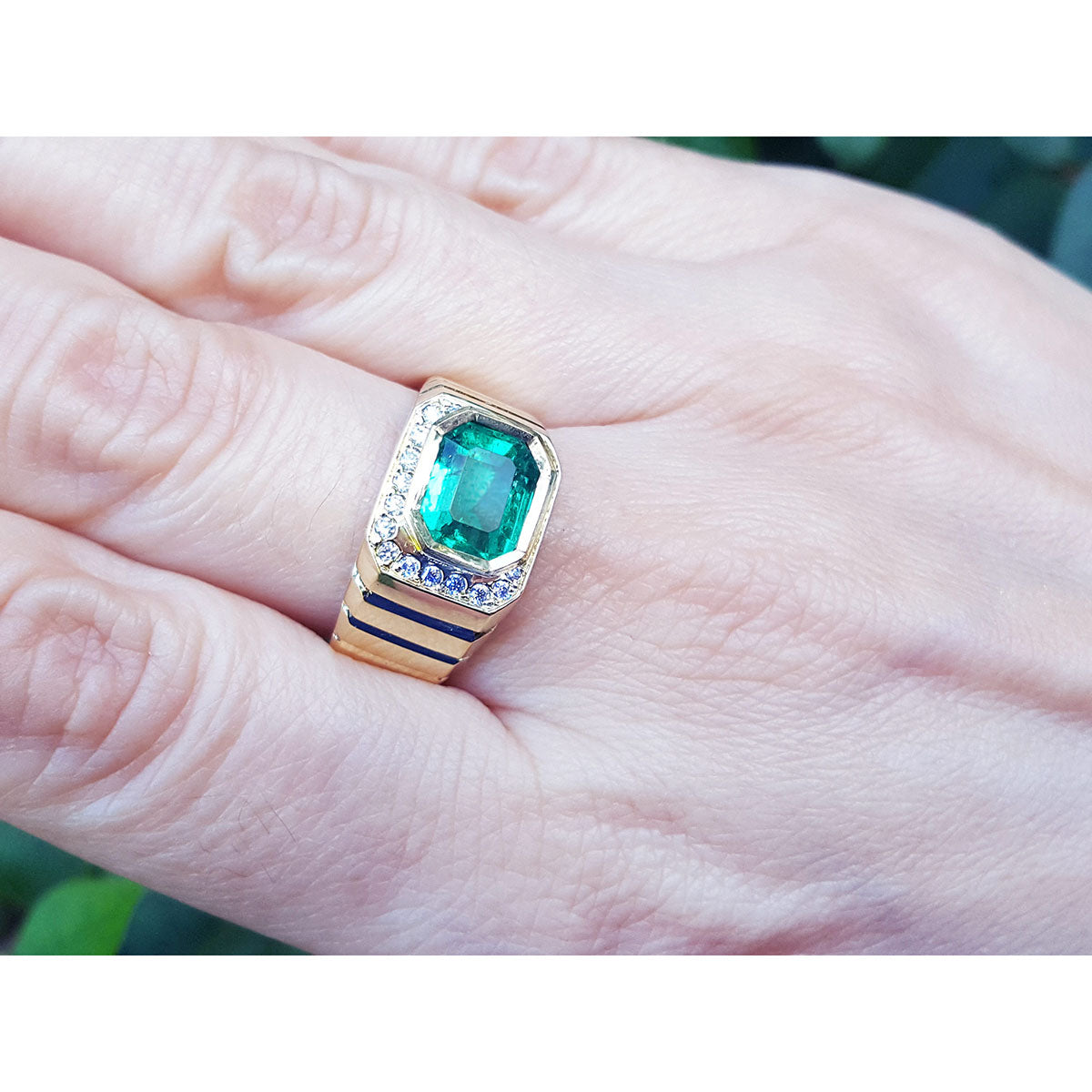 A gold genuine colombian emerald ring being worn by a hand between fingers.