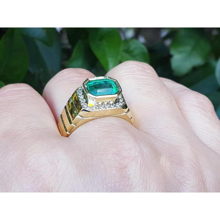 Men's 18K yellow gold ring with a bezel-set emerald-cut green emerald and diamond accents.