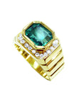 Gold ring for men with a rectangular colombian emerald and diamond accents on a white background