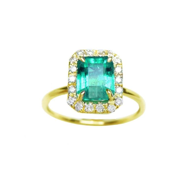 A rectangular emerald encircled into a halo natural diamond ring in 14k yellow gold.