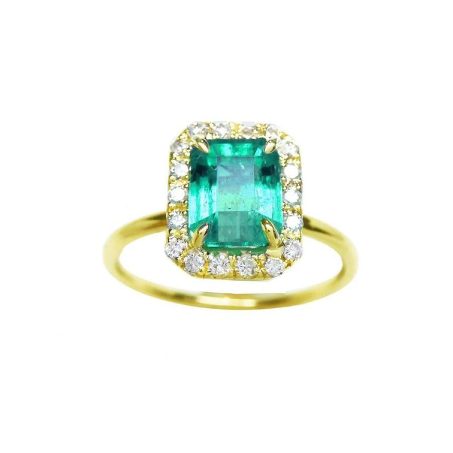 A rectangular emerald encircled into a halo natural diamond ring in 14k yellow gold.