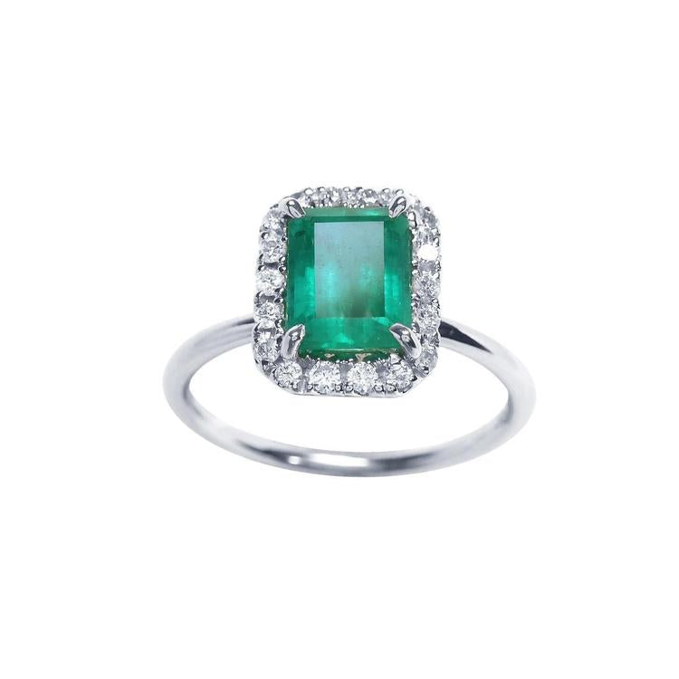 Emerald-cut Muzo emerald ring with halo diamonds in 14K white gold.