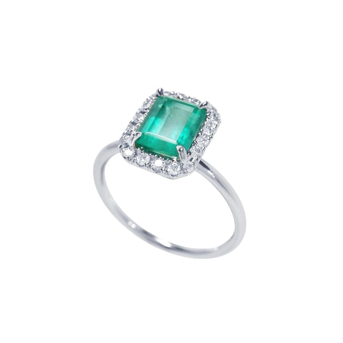 A semi-lateral view of a natural colombian emerald into a halo diamond in 14k white gold ring.