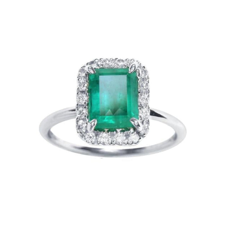 A rectangular emerald-cut encircled by a halo natural diamond emerald ring in 14k white gold.
