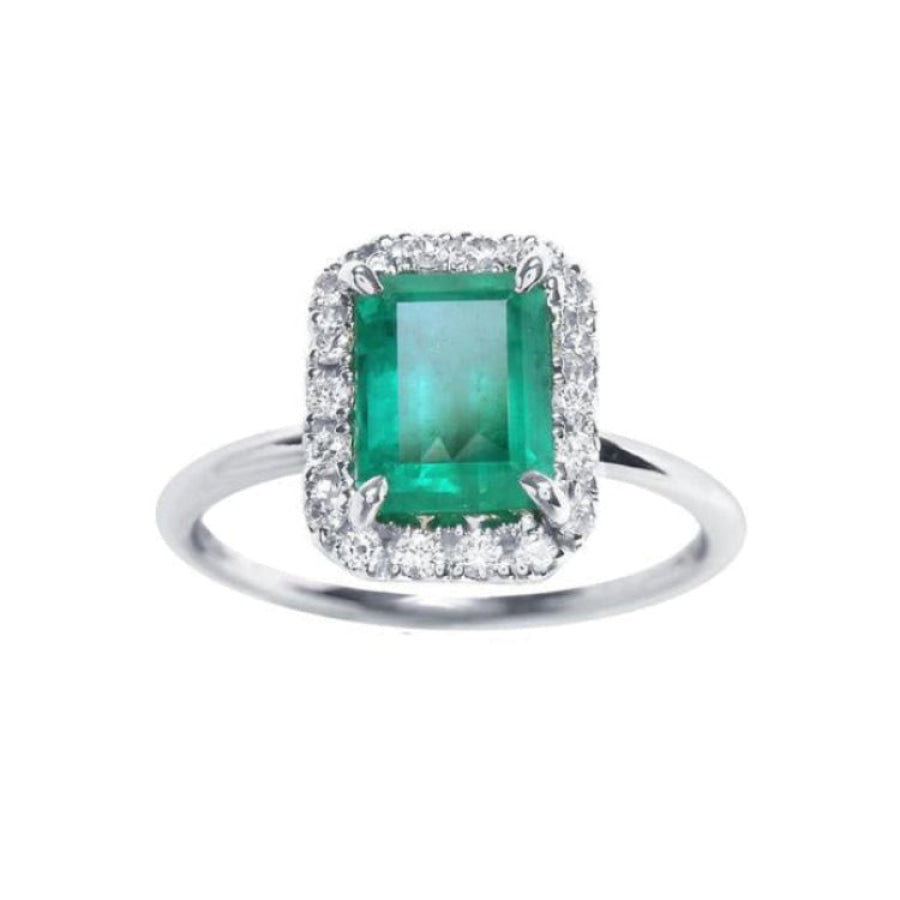 A rectangular emerald-cut encircled by a halo natural diamond emerald ring in 14k white gold.