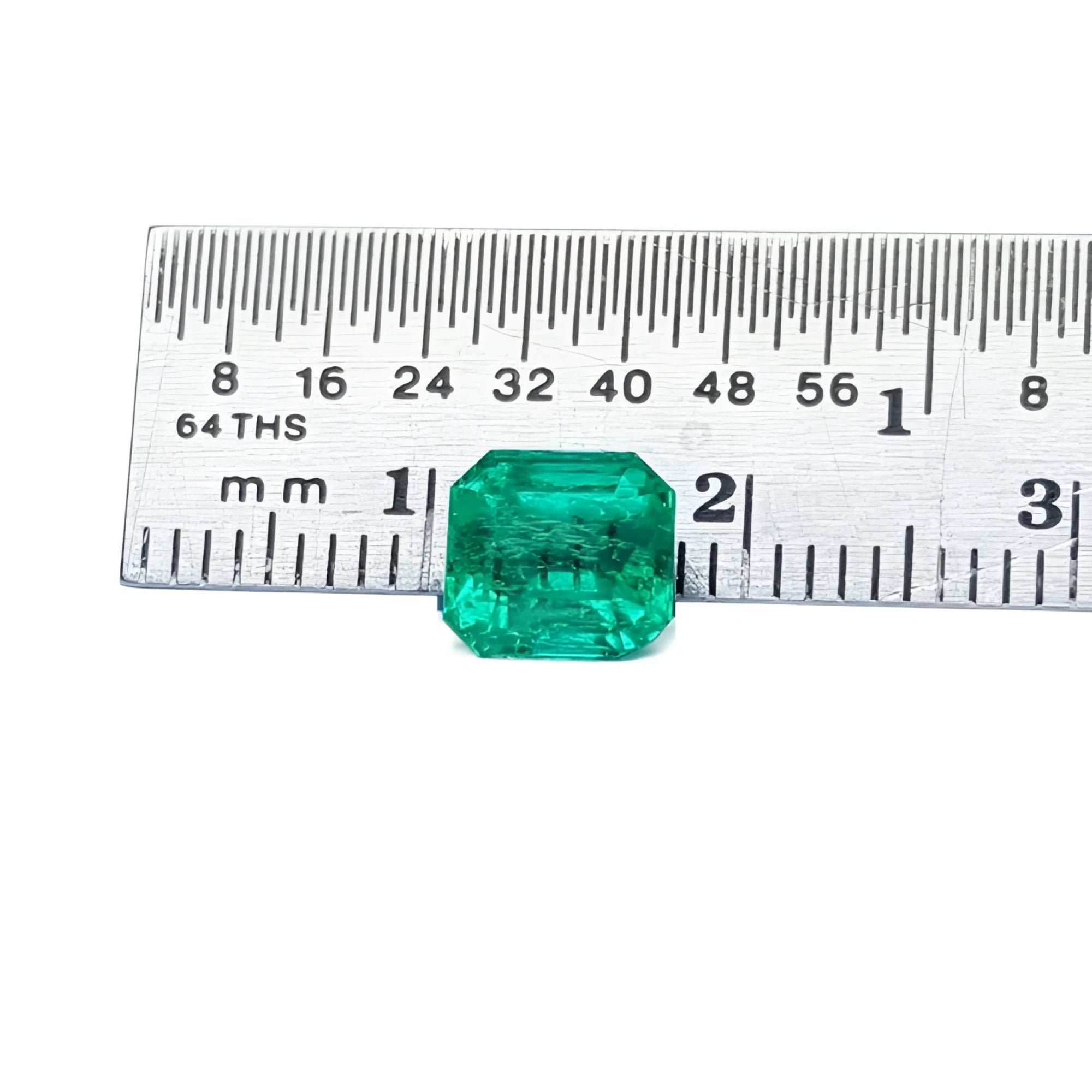 1.55 carat emerald-cut Muzo Colombian loose emerald, sparkling medium bluish green, next to a ruler.