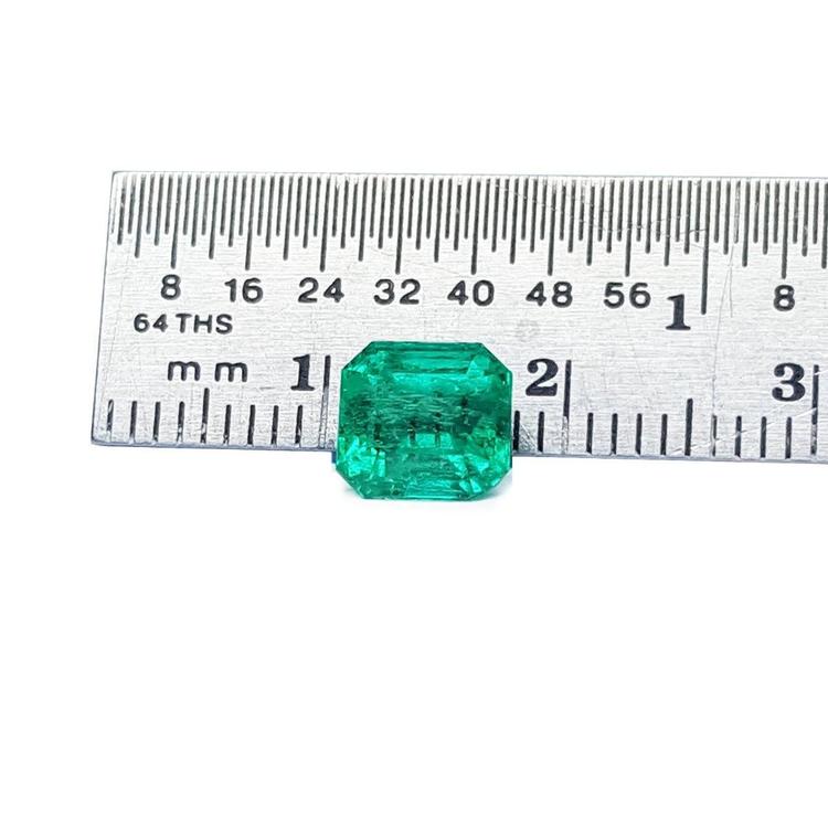 1.55 carat emerald-cut Muzo Colombian loose emerald, sparkling medium bluish green, next to a ruler.