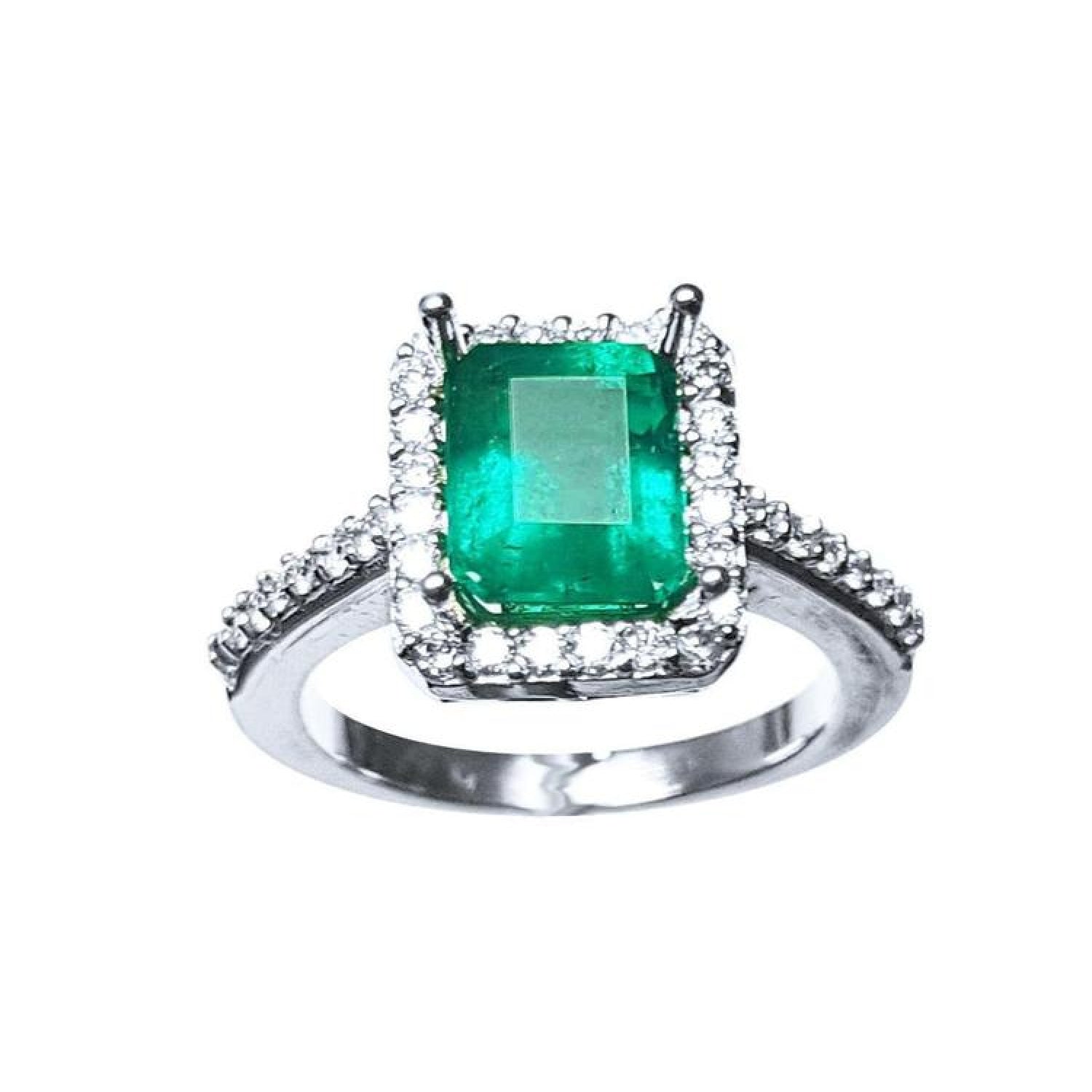 Emerald-cut Muzo Colombian emerald ring with diamond halo and pavé band.