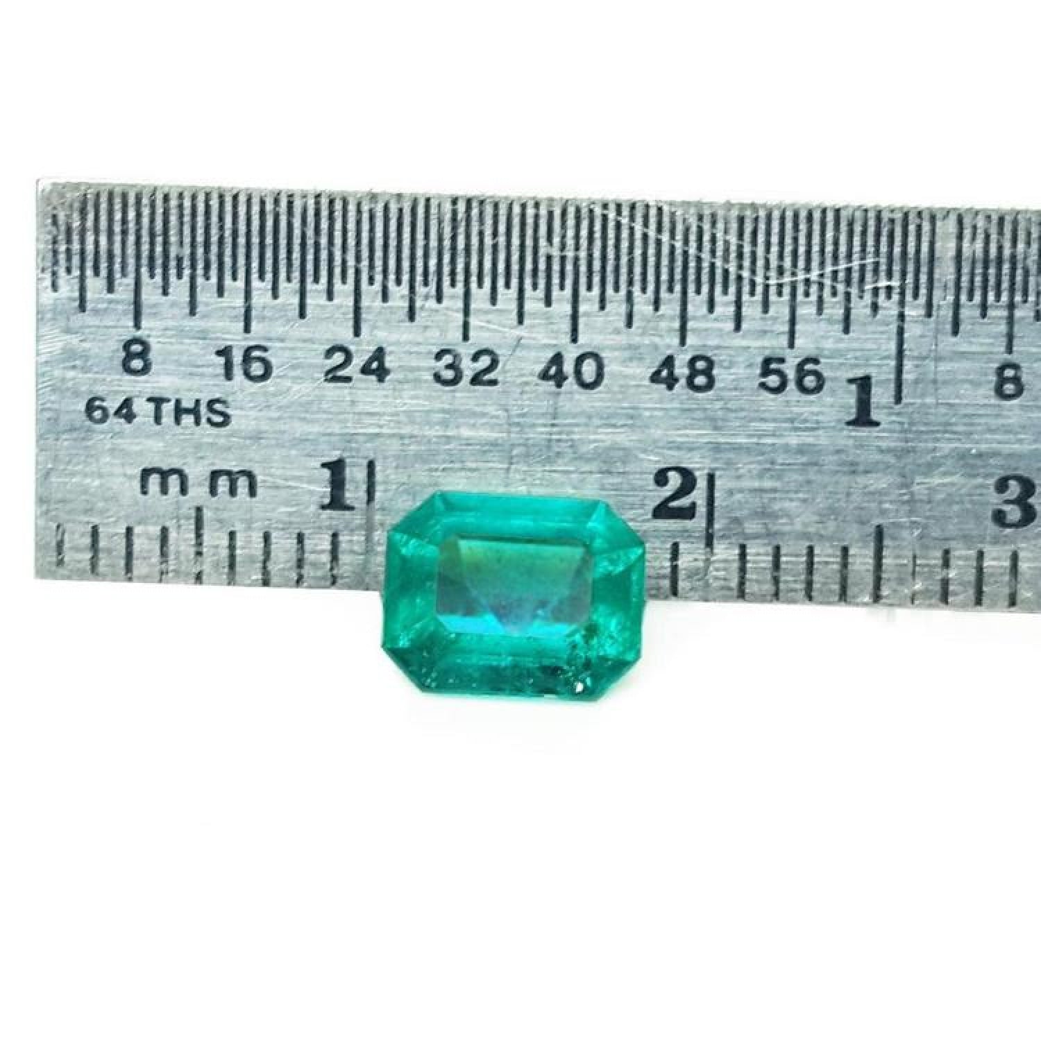 1.57 carat emerald-cut Muzo Colombian emerald, sparkling medium bluish green, next to a ruler.
