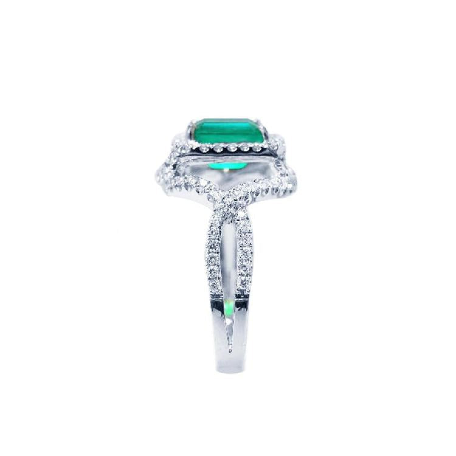 Emerald-cut natural emerald ring with halo diamonds on an 18K white gold split shank band.