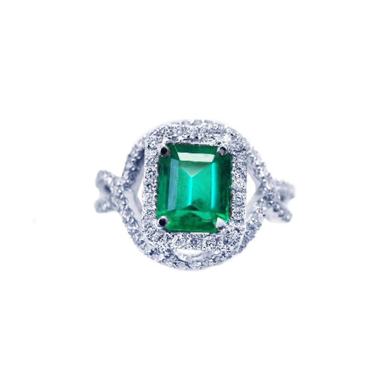 An emerald-cut natural colombian emerald in a halo diamond ring for ladies made of 18k white gold.