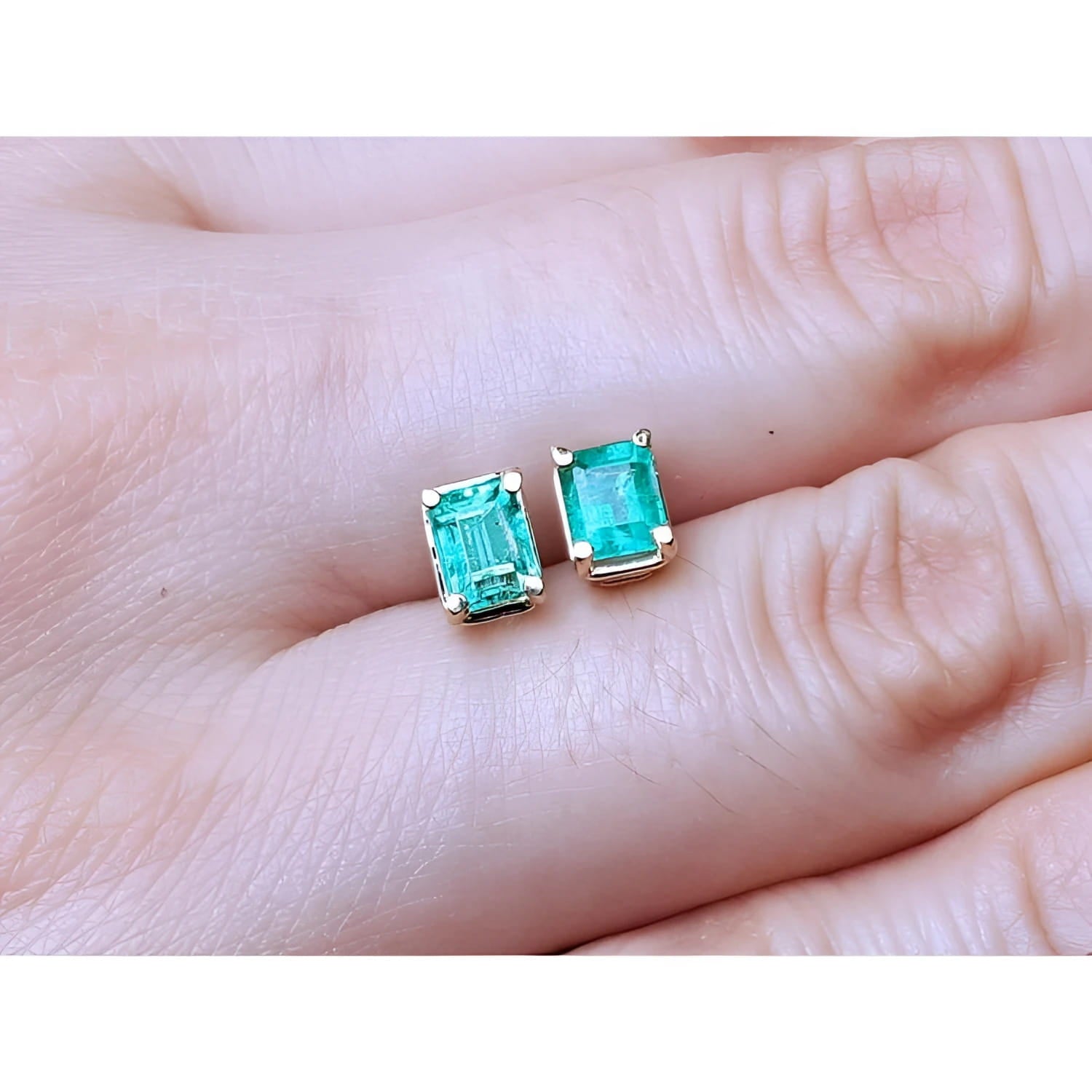 Emerald-cut natural emerald stud earrings, 1.29 ct, set in 14K yellow gold.