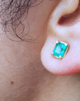 Close-up of an earlobe wearing a emerald stud earring.