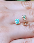Push backs emerald stud earrings on a hand.