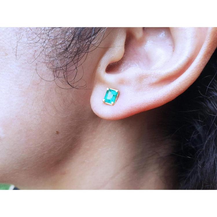 Emerald-cut natural emerald stud earring in 14K yellow gold, worn on an ear.