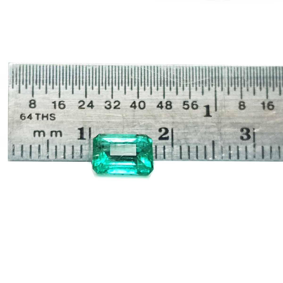 Affordable emerald-cut loose Colombian emerald front next to a ruler for measuring size