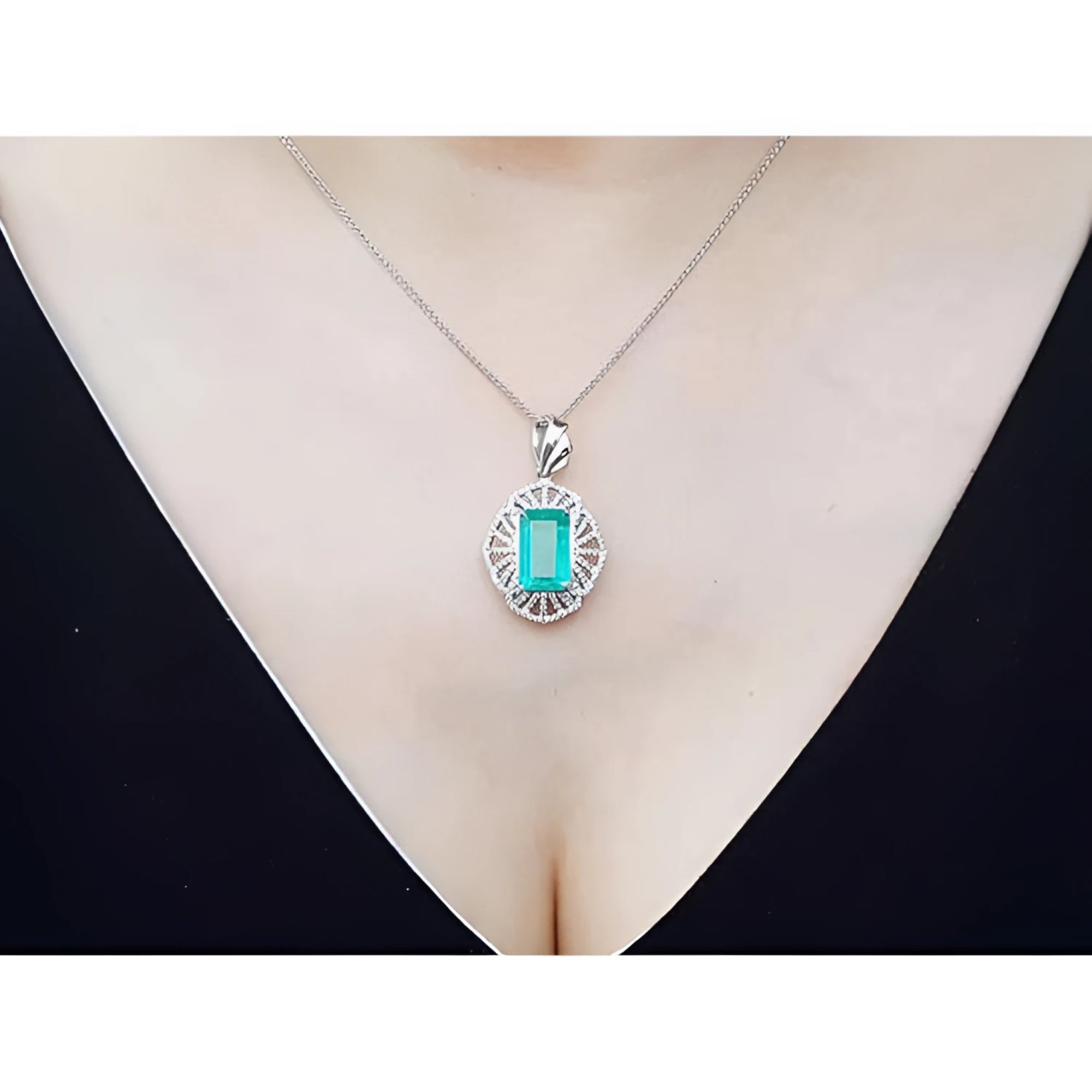 Emerald-cut emerald pendant with natural diamonds on a 14K white gold chain, worn on a woman's neck.