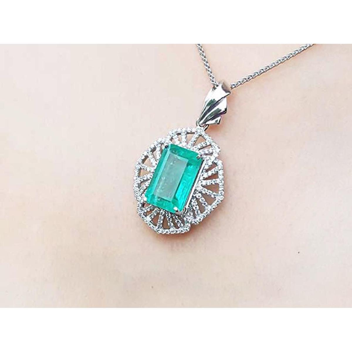 Emerald pendant necklace on a person's neck against a neutral background