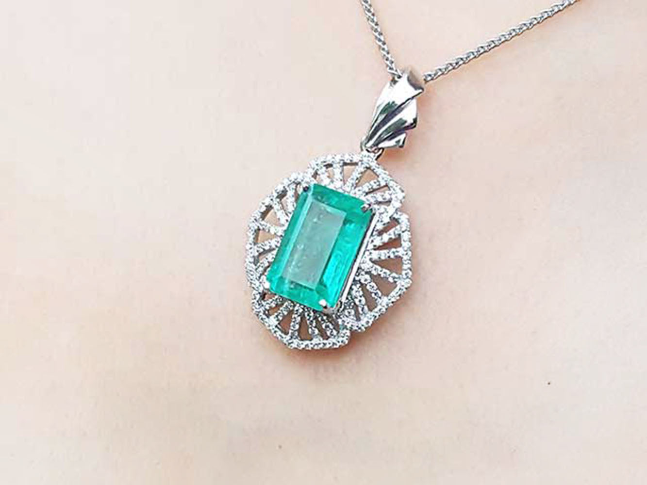 Emerald pendant necklace on a person's neck against a neutral background