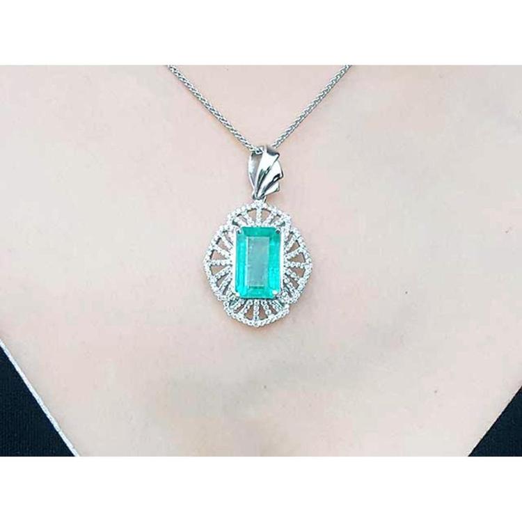 A rectangular natural emerald pendant in white gold and accent diamonds on topside view.