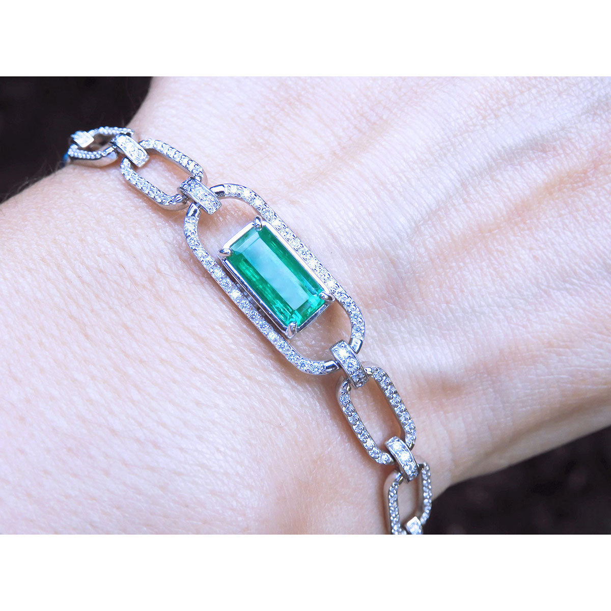 A paperclip bracelet with a natural Colombian emerald accented with diamonds, crafted in 14k white gold on a wist.