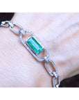 A paperclip bracelet with a natural Colombian emerald accented with diamonds, crafted in 14k white gold on a wist.