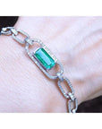 A paperclip bracelet with a natural Colombian emerald accented with diamonds, crafted in 14k white gold on a wist.