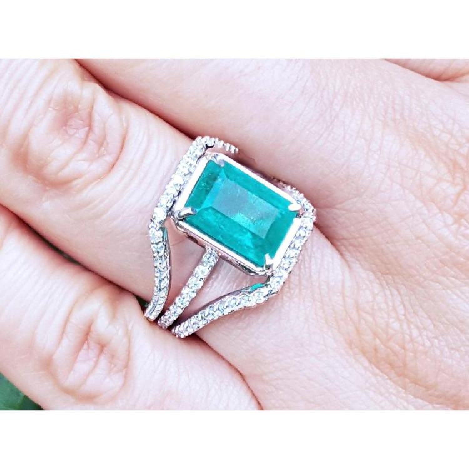 Emerald-cut 3.90 ct bluish-green emerald ring with triple diamond rows on 14K white gold.