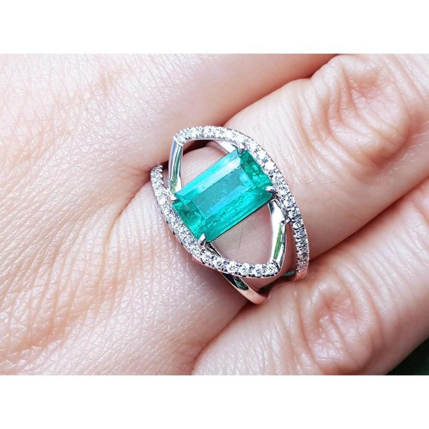 Rectangular emerald-cut emerald ring with diamond double halo and split shank in 14K white gold.