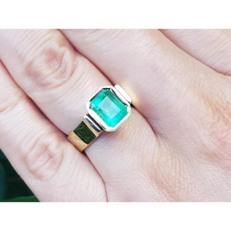 Emerald-cut 2.05 ct. emerald solitaire ring, bezel set in high polish 14K gold on a hand.