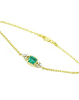 A yellow gold bracelet with a Muzo colombian emerald on a white background.