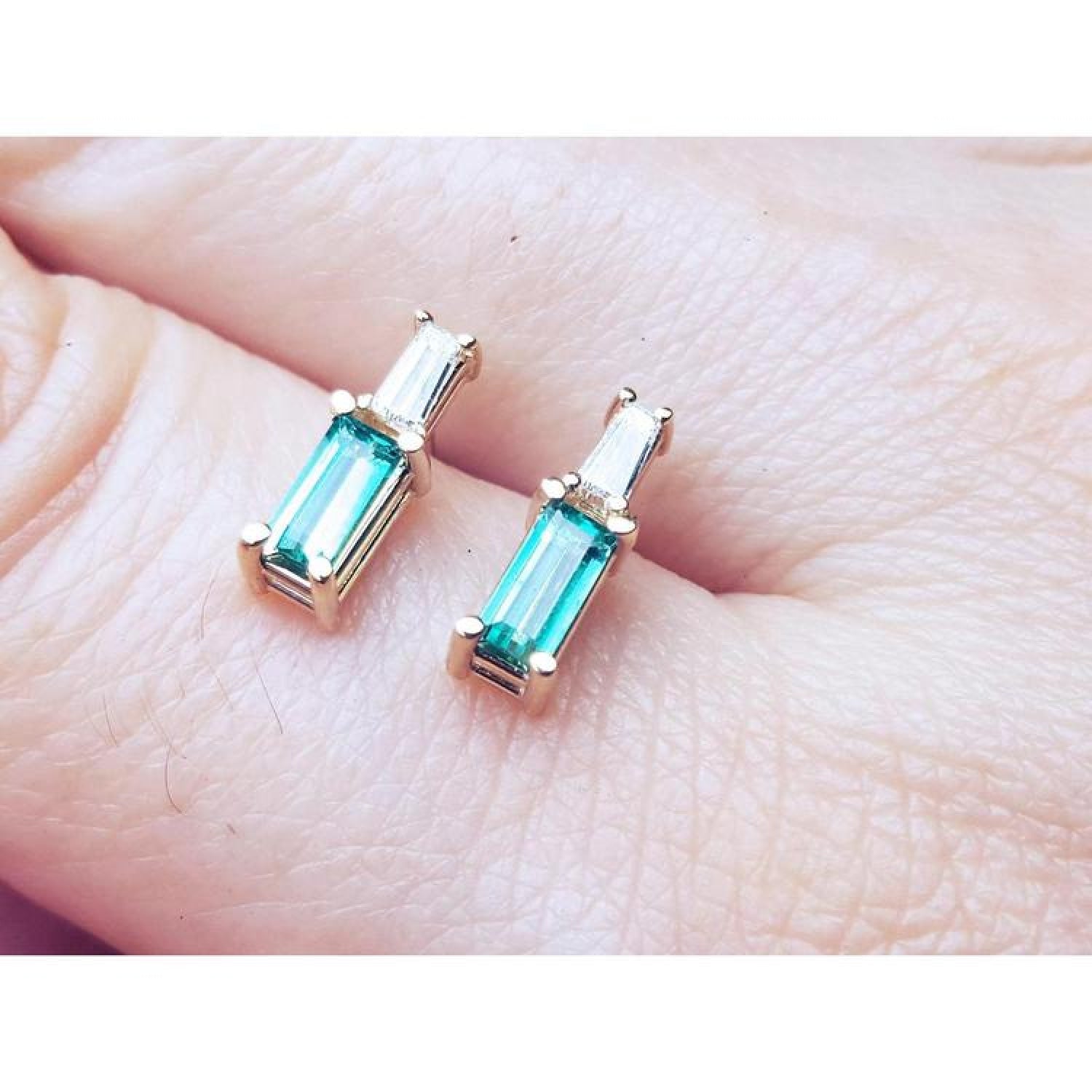Minimalist 14K gold stud earrings with baguette emeralds and tapered baguette diamonds.