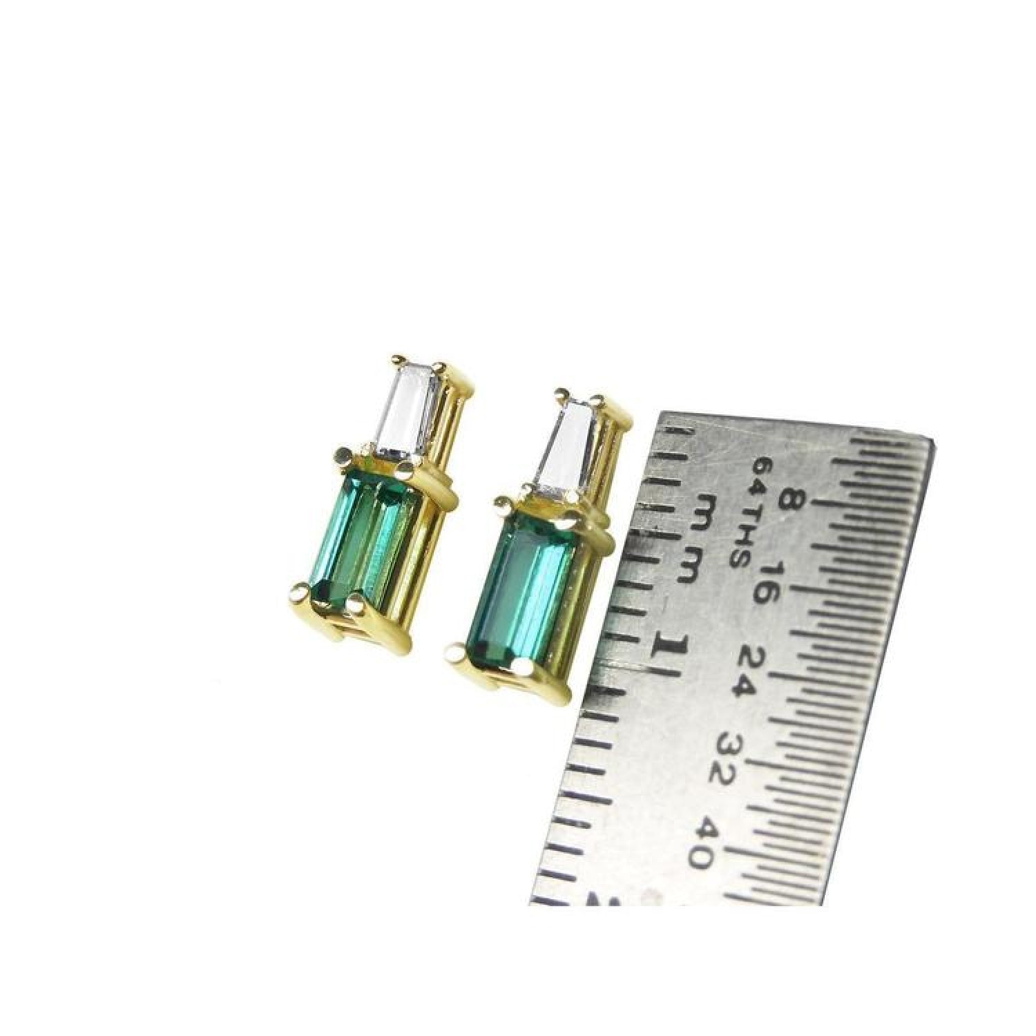 Minimalist 14K gold baguette emerald and diamond stud earrings, shown with a ruler for scale.