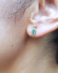 Close-up of an ear wearing a baguette cut emerald earring.