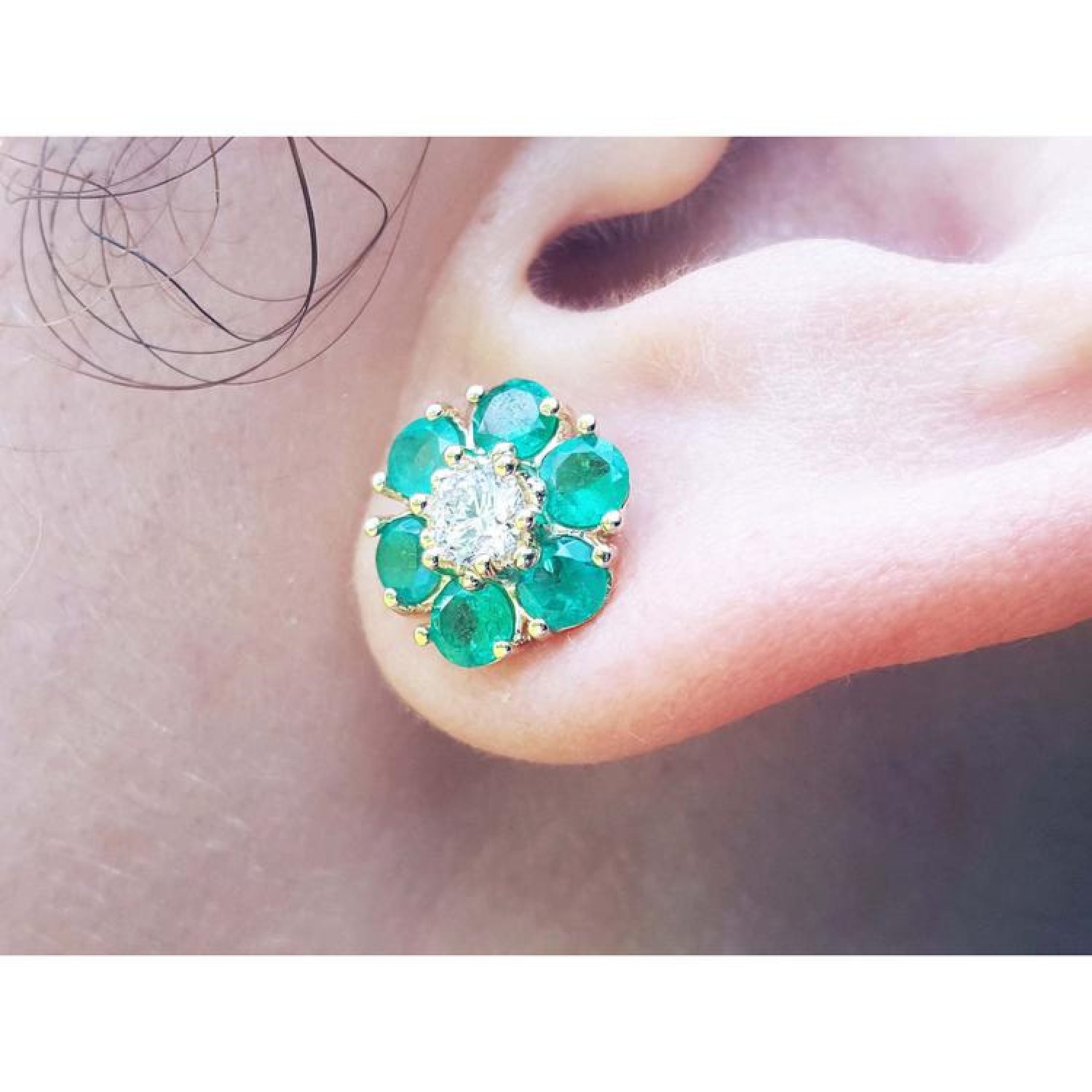 18K yellow gold Colombian emerald and diamond cluster earring on an ear.