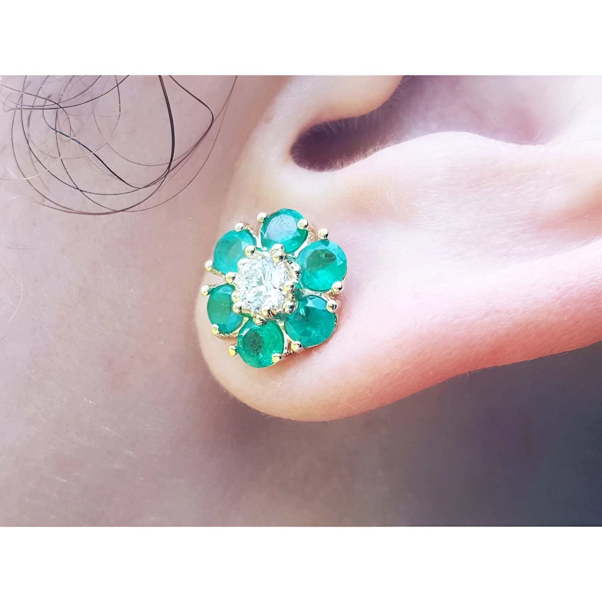 18K yellow gold Colombian emerald and diamond cluster earring on an ear.