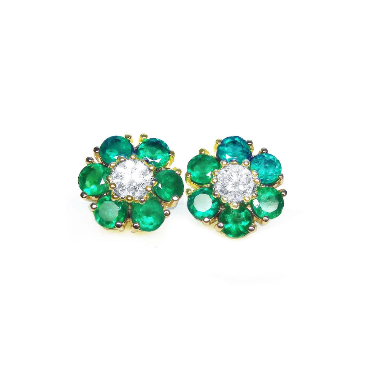 Pair of emerald and diamond stud cluster earrings on a topside view