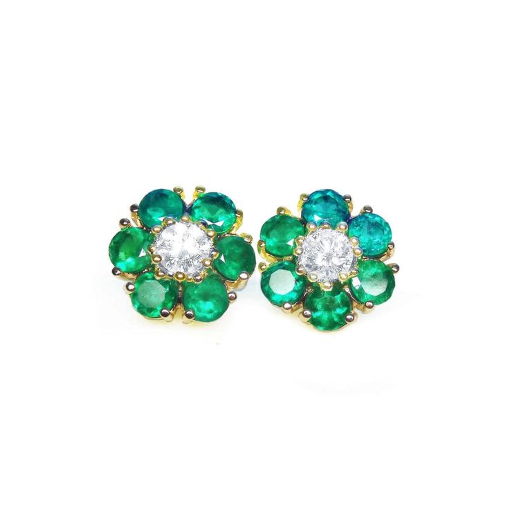 Pair of emerald and diamond stud cluster earrings on a topside view
