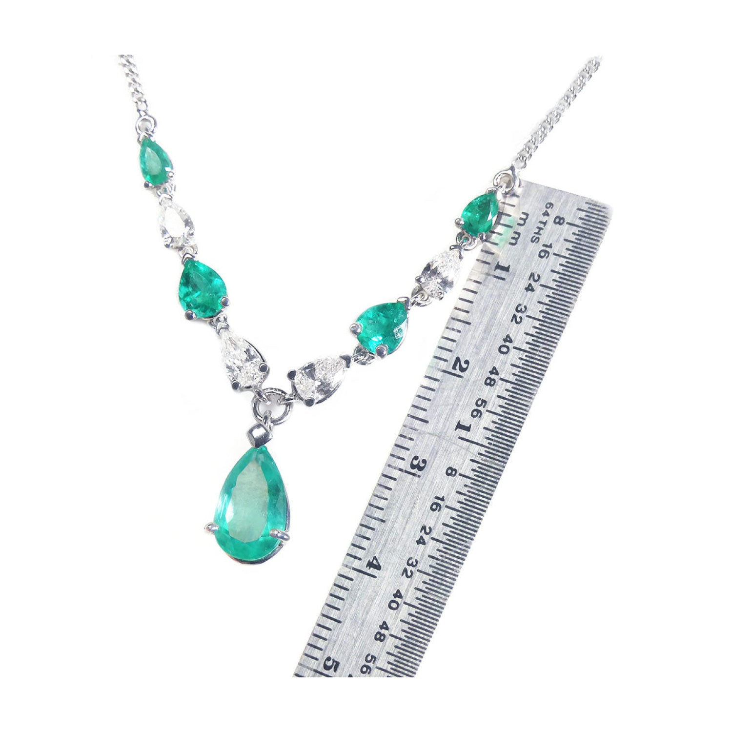 14k white gold necklace with pear-shaped emeralds and diamonds, shown with a ruler for scale.