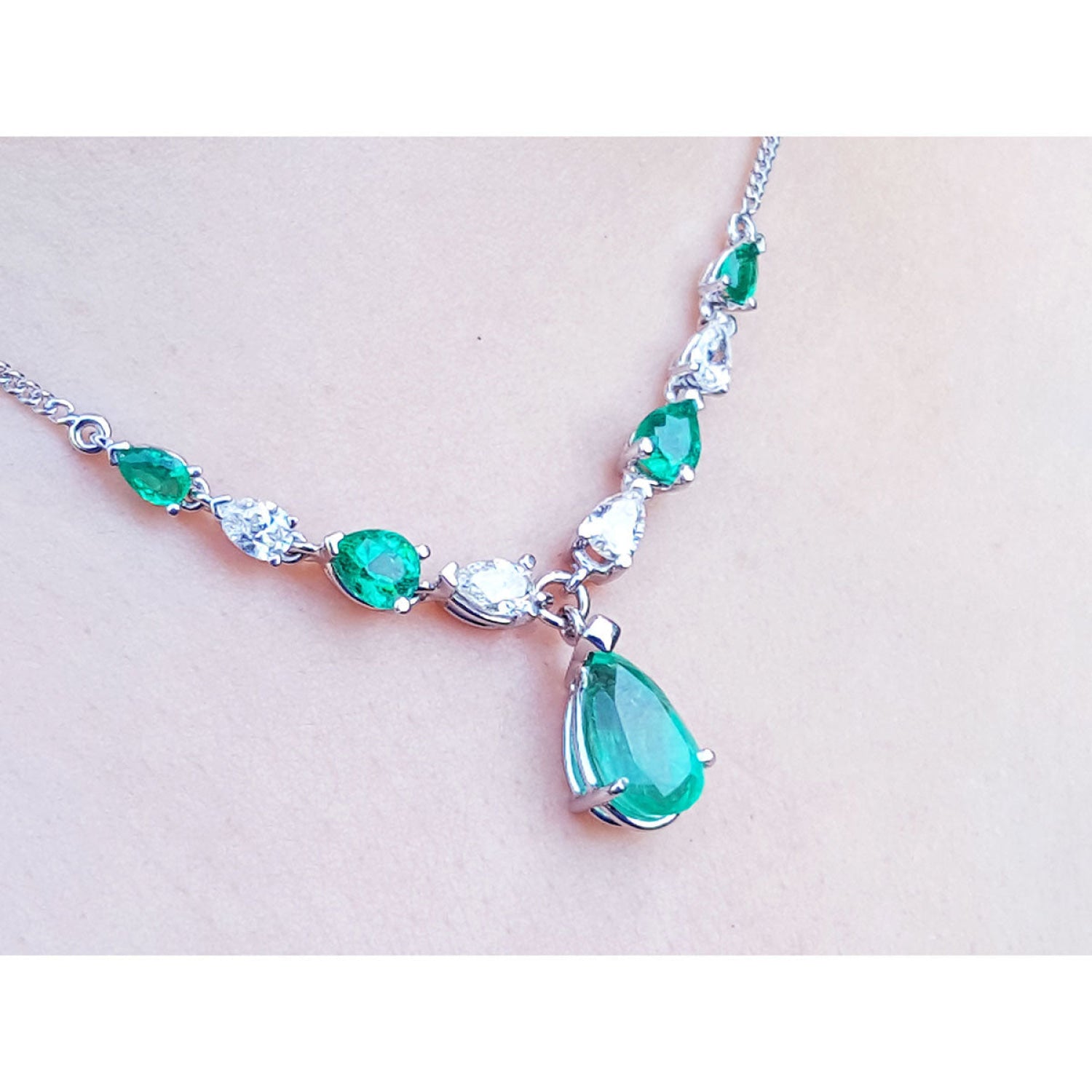 14k white gold necklace with pear-shaped emeralds and diamonds, featuring a large emerald drop pendant.