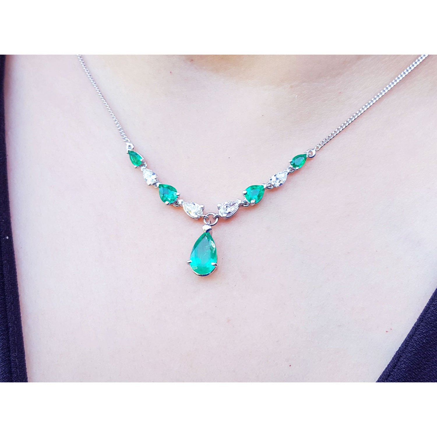 14k white gold necklace with pear-shaped emeralds and diamonds, featuring a large emerald drop.