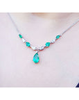 14k white gold necklace with pear-shaped emeralds and diamonds, featuring a large emerald drop.