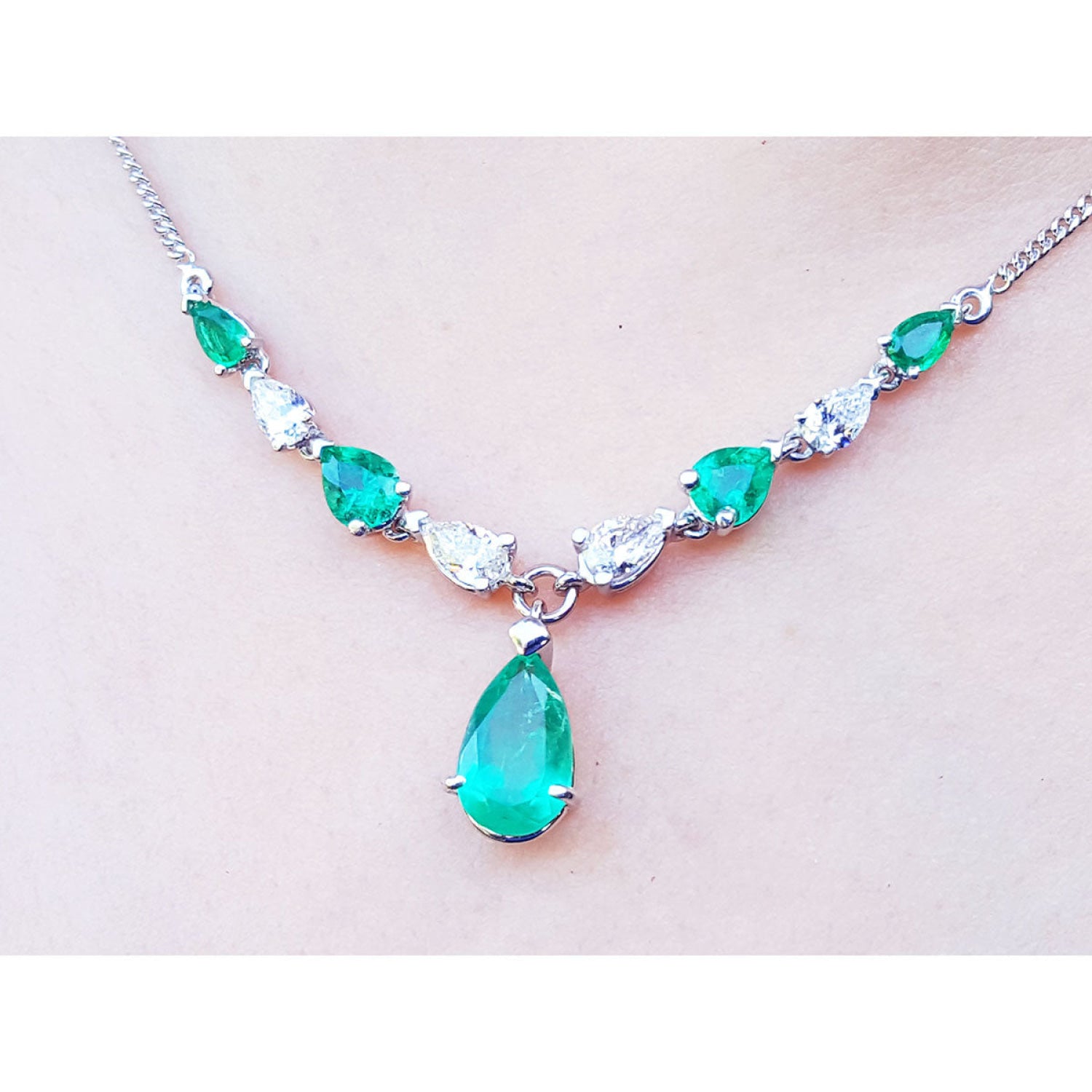 14k white gold necklace with pear-shaped emeralds and diamonds, featuring a large emerald drop pendant.