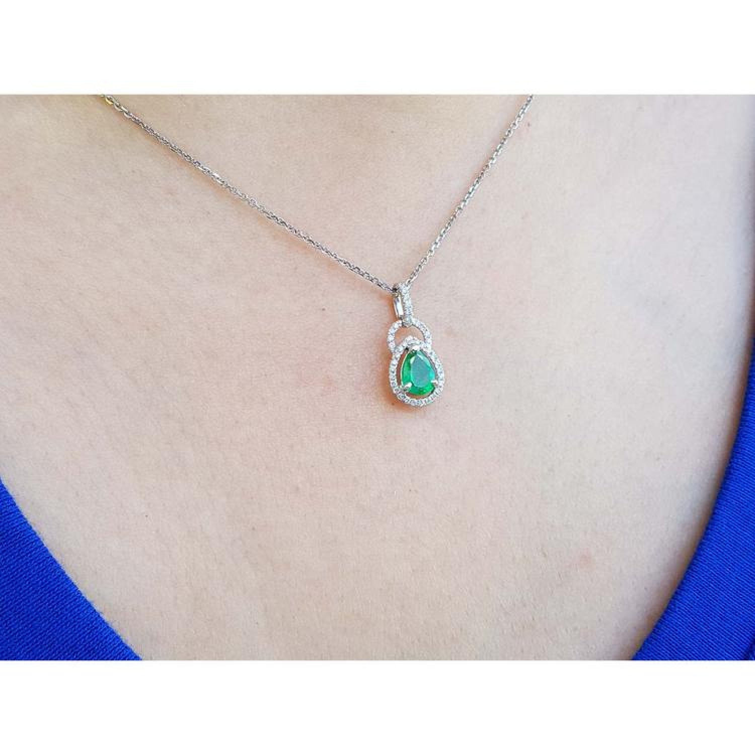 Pear-shaped Colombian emerald and diamond halo pendant in 14K white gold on a silver chain.
