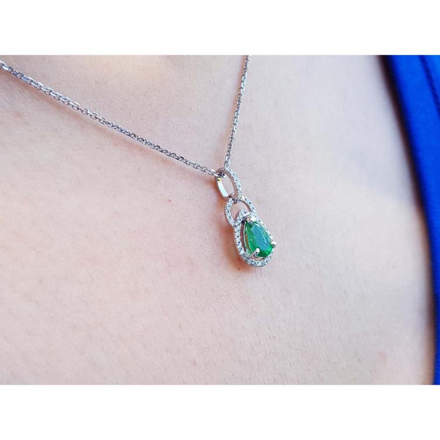 Pear-shaped Colombian emerald and diamond halo pendant in 14K white gold on a delicate chain.