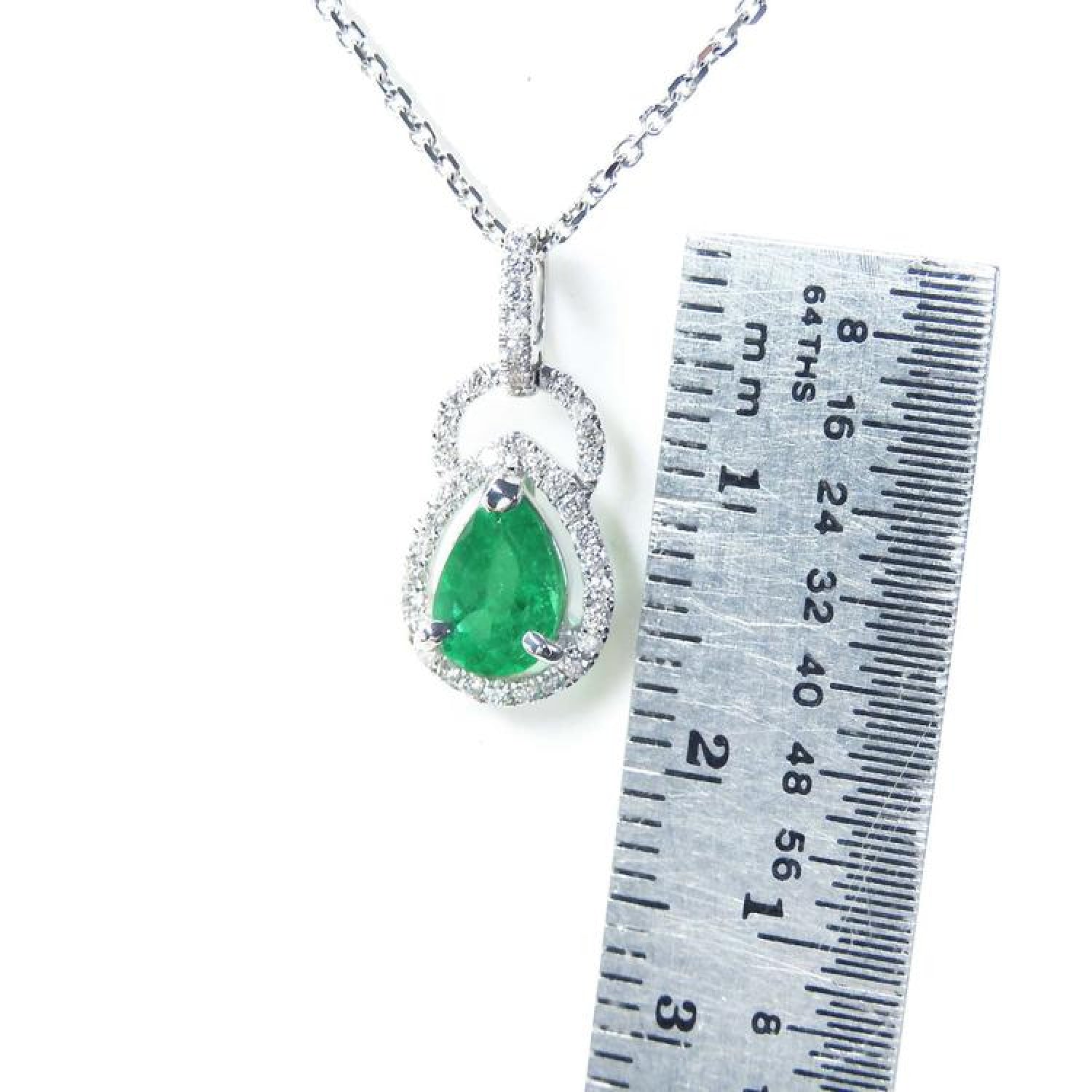 Pear-shaped natural Colombian emerald and diamond halo pendant in 14K white gold, shown with a ruler.
