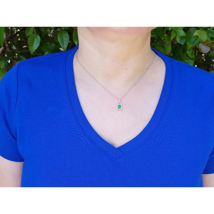 Pear-shaped Colombian emerald and diamond halo pendant on a 14K white gold chain, worn on a woman's neck.