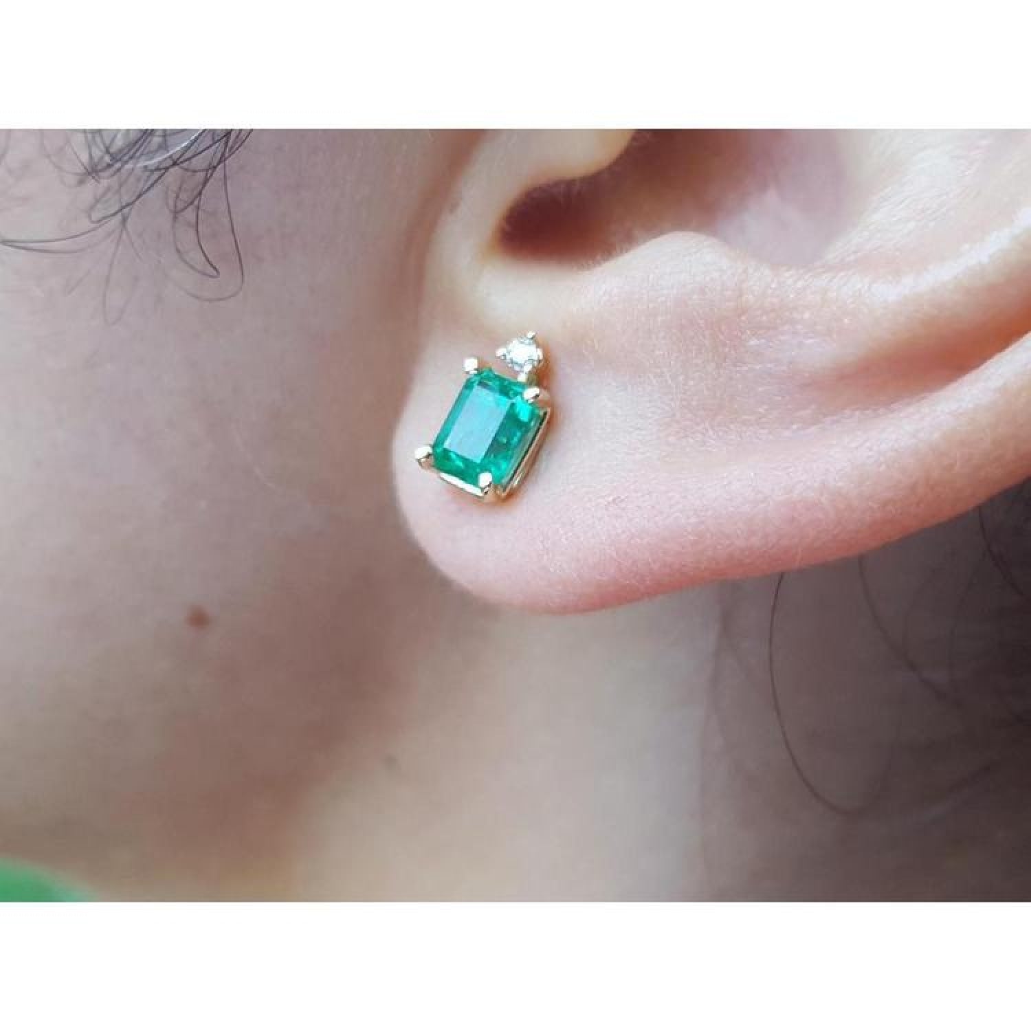 Colombian emerald and diamond stud earring in 14K yellow gold, worn on an ear.