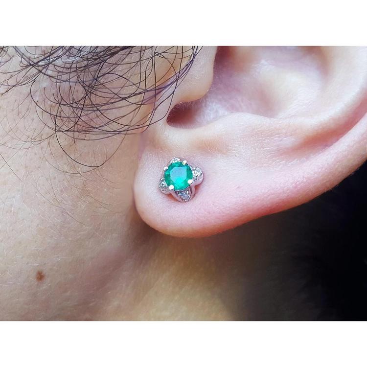 An ear wearing an emerald and diamond tulip stud earring in white gold.