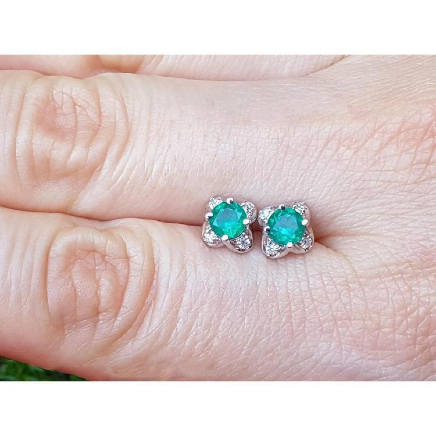 Emerald and diamond tulip stud earrings in 14K white gold, featuring deep bluish-green emeralds.